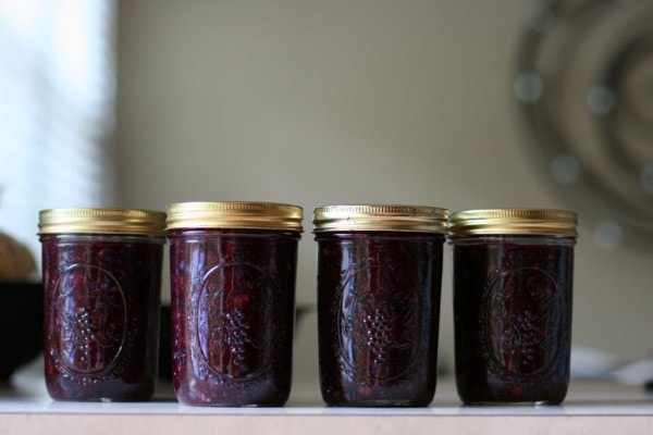Four Mason jars of blueberry jam.