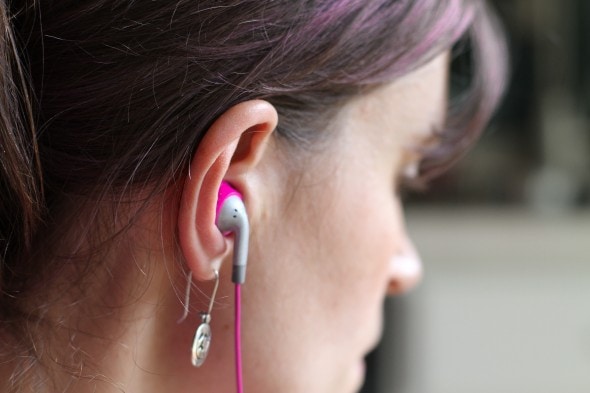 An ear with a pink earbud inserted.