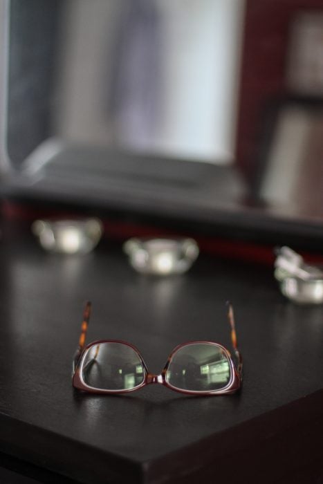 A pair of glasses on a black dresser top.