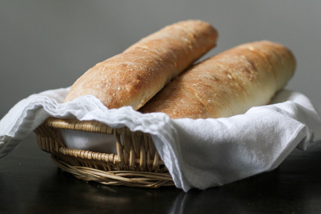 Two loaves of homemade French bread in a basket.