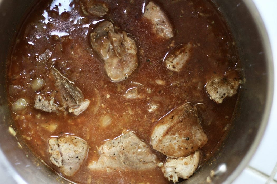 pork chunks in a pot of tomato broth.