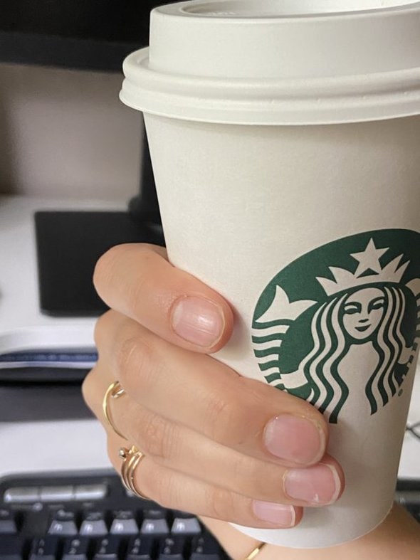 Kristen's hand holding a Starbucks drink.