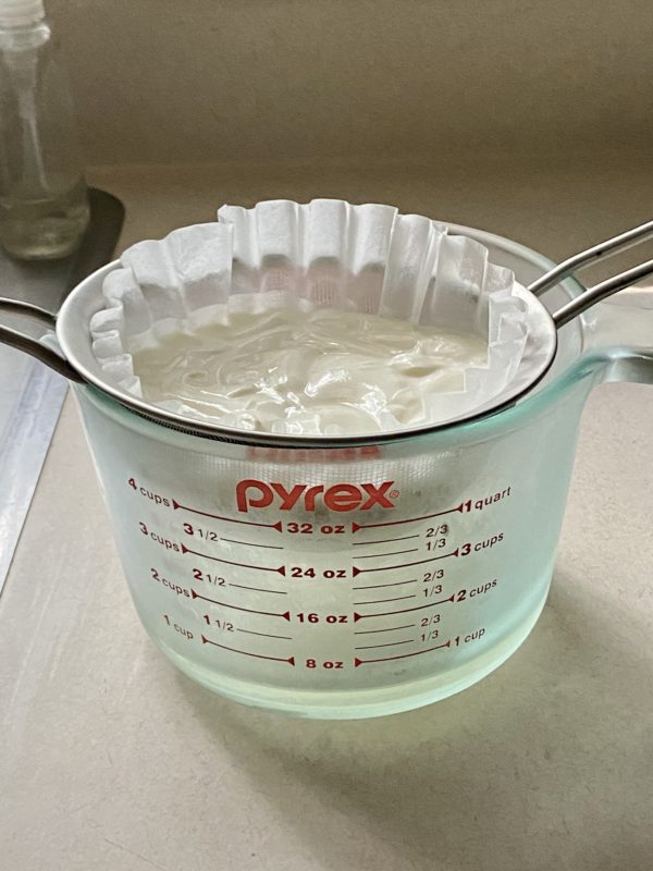 yogurt draining in a measuring cup.