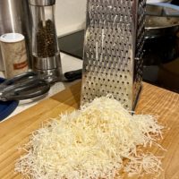 shredded Parmesan on a wood cutting board.